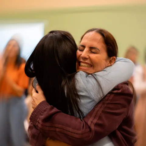 Duas mulheres se abraçando durante um encontro da Comunidade Vitória e Paz.